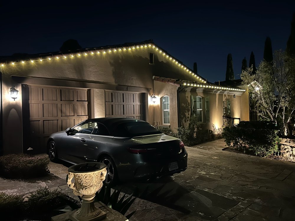 Warm white roofline lighting over a driveway