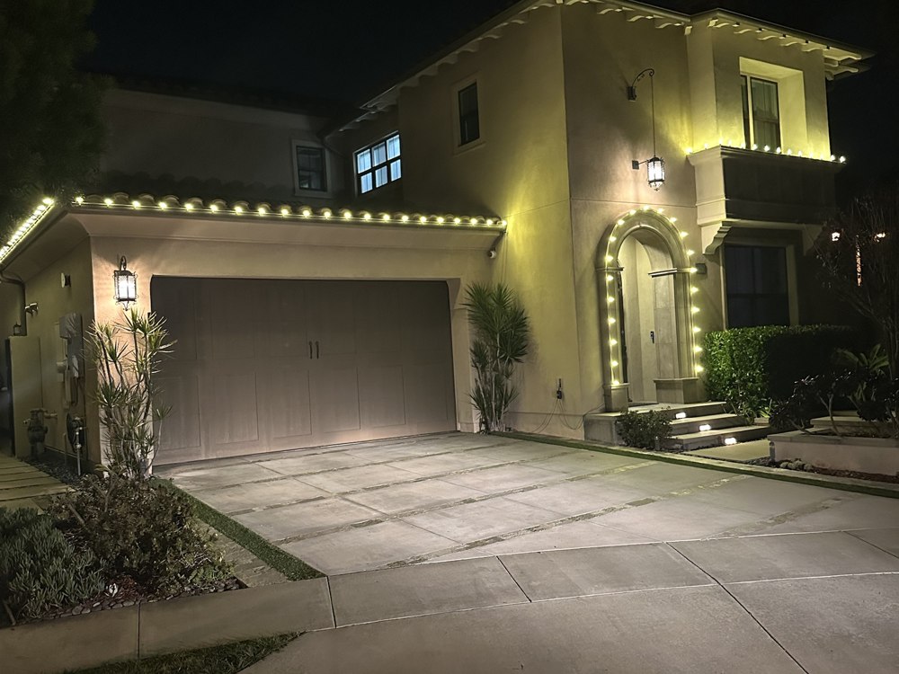 Home with lit garage archway and roofline